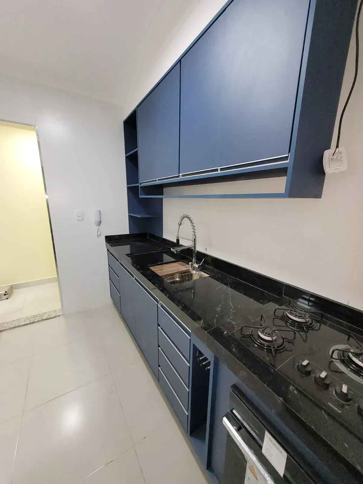 Cozinha corredor planejada com armários azuis e bancada de granito preto