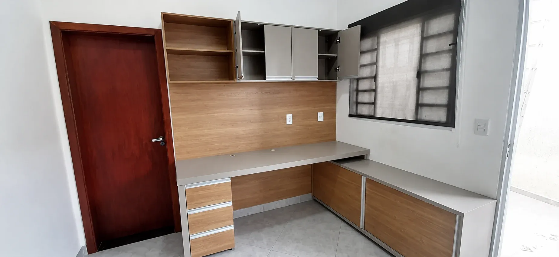 Home office planejado com bancada em L e espaço para estudos